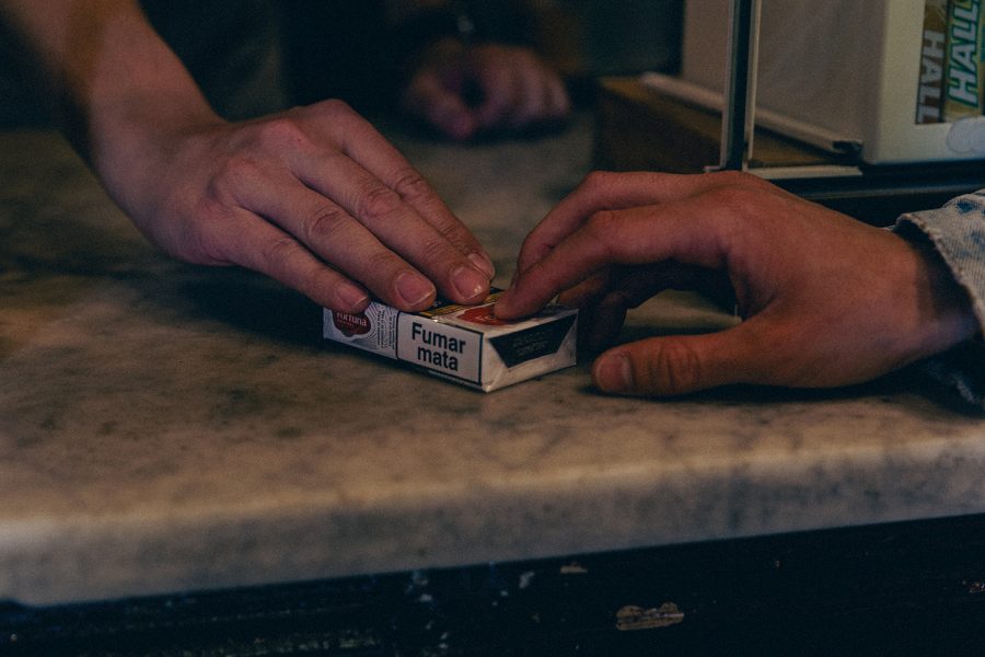 Dues mans intercanvien un paquet de tabac sobre el taulell d’un estanc. A la capsa hi apareix l’advertència sanitària «Fumar mata»